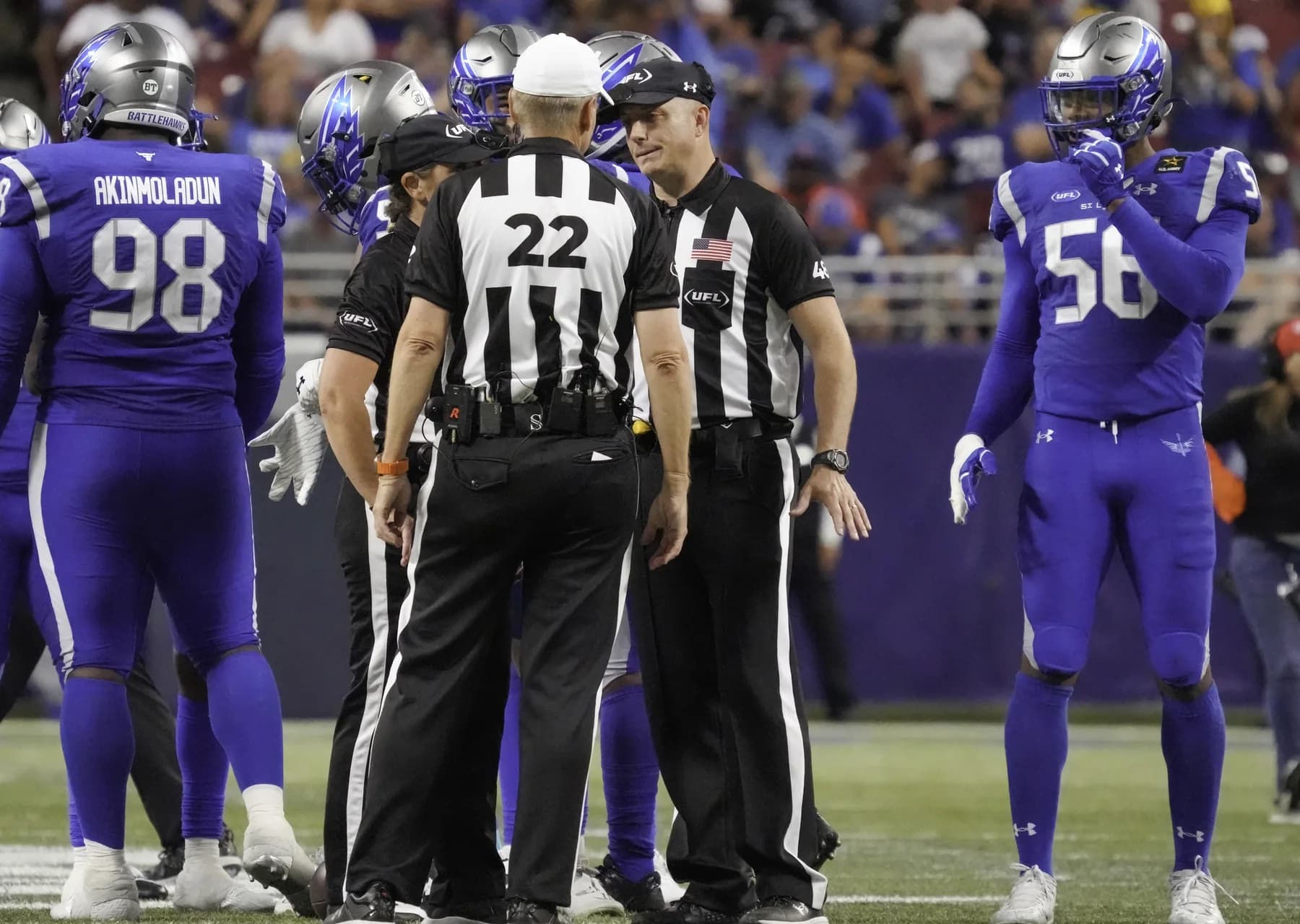 Michael Kennedy in officiating stripes, talking with the referee between plays at a UFL game